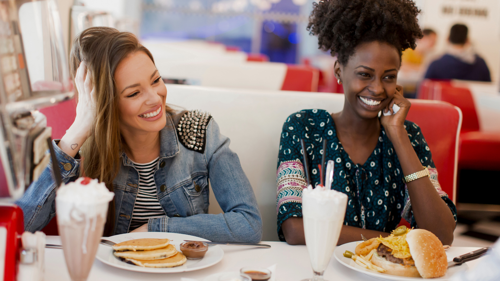 two women have a great time eating at a diner with milk shakes